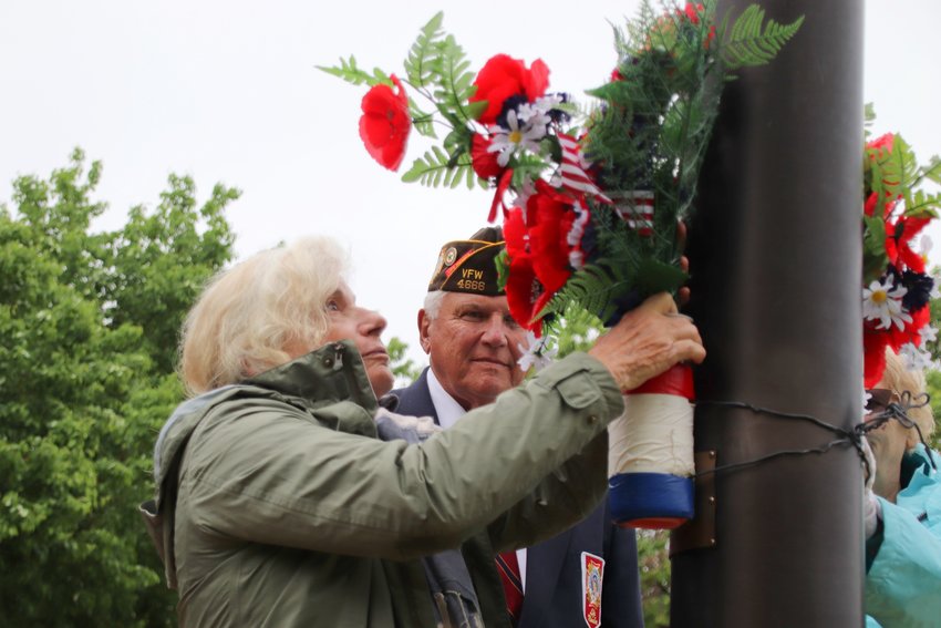 Elizabeth Marzonie, left, backed by her husband Jim, affixes poppies to the flagpole at the World War II memorial.